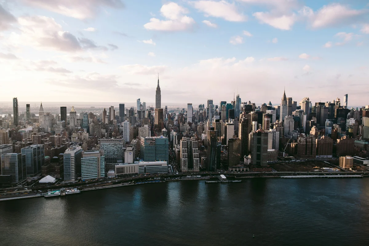 Midtown Manhattan seen across the East River, with the Empire State and Chrysler buildings in soft afternoon light.